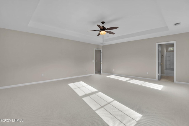 spare room featuring ceiling fan, a raised ceiling, and light carpet