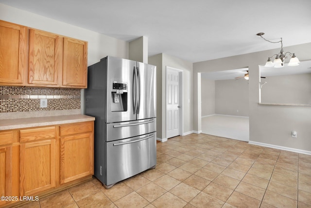 kitchen with light tile patterned flooring, decorative light fixtures, stainless steel fridge with ice dispenser, ceiling fan with notable chandelier, and decorative backsplash