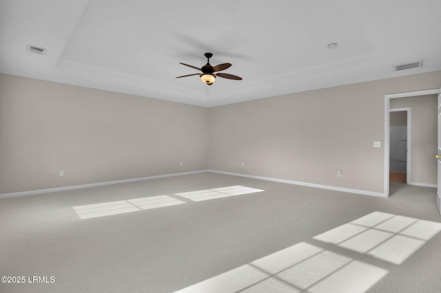 unfurnished room featuring light carpet, a tray ceiling, and ceiling fan