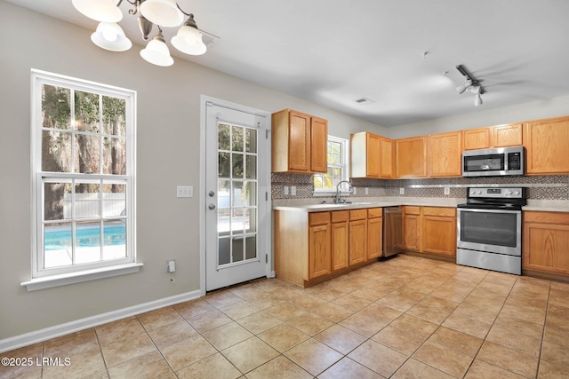 kitchen with sink, an inviting chandelier, light tile patterned floors, appliances with stainless steel finishes, and backsplash