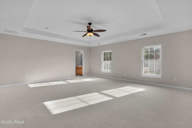 unfurnished room with a raised ceiling, light colored carpet, and ceiling fan