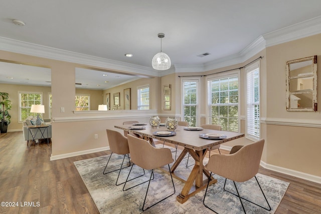 dining space featuring hardwood / wood-style flooring, ornamental molding, and a healthy amount of sunlight