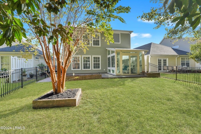 rear view of house with a yard, a patio area, and a sunroom