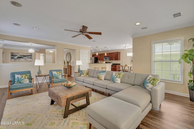 living room with crown molding, ceiling fan, and light wood-type flooring