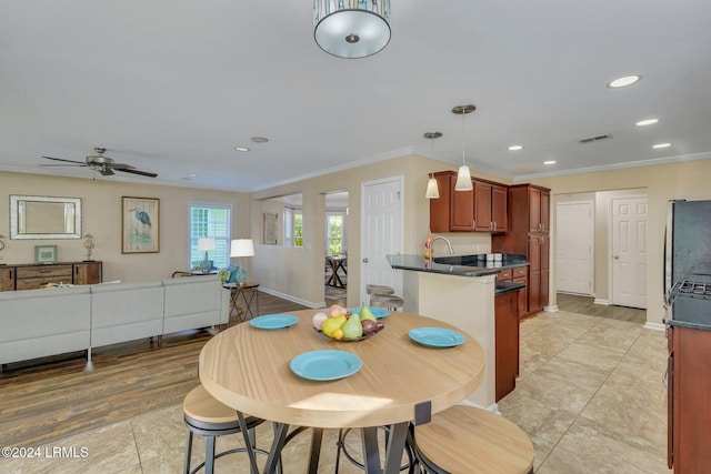 tiled dining room with ceiling fan and ornamental molding