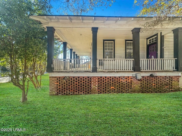 rear view of property featuring a lawn and covered porch