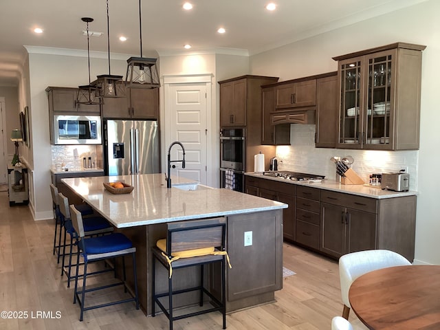 kitchen with sink, hanging light fixtures, stainless steel appliances, a center island with sink, and custom exhaust hood