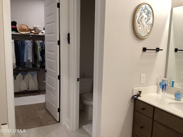 bathroom with vanity, toilet, and hardwood / wood-style floors