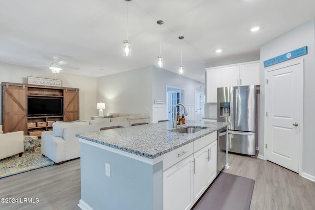 kitchen with an island with sink, sink, white cabinets, stainless steel appliances, and a barn door