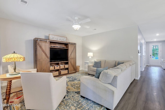 living room with dark hardwood / wood-style floors, ceiling fan, and a barn door