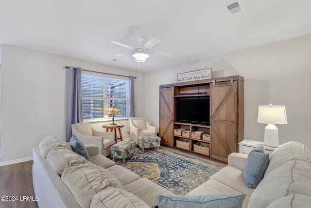 living room with ceiling fan, wood-type flooring, and a barn door