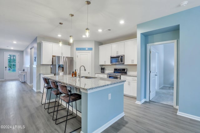 kitchen featuring a kitchen island with sink, sink, stainless steel appliances, and white cabinets