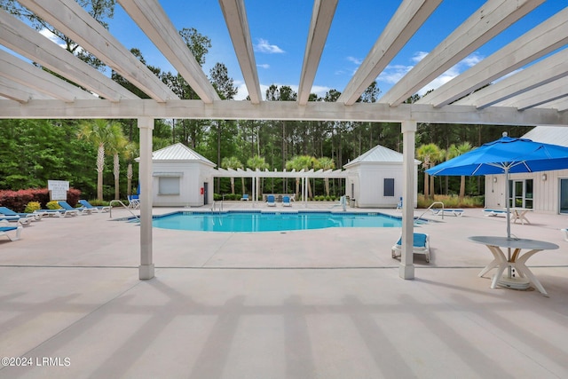 view of swimming pool with an outbuilding, a pergola, and a patio area