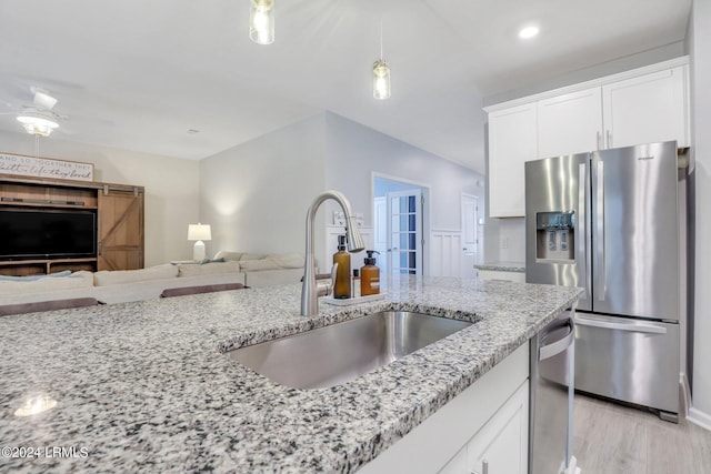 kitchen with white cabinetry, appliances with stainless steel finishes, sink, and light stone counters