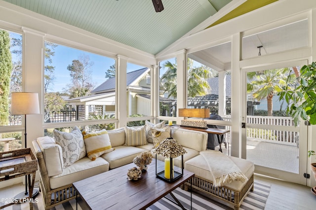 sunroom / solarium with lofted ceiling, a ceiling fan, and a wealth of natural light