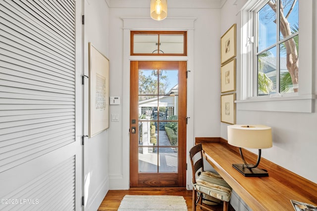 doorway to outside with a healthy amount of sunlight, light wood-type flooring, and baseboards