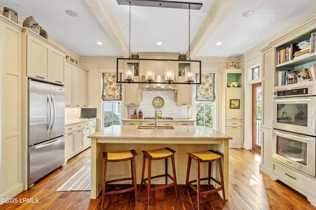 kitchen featuring light stone counters, a breakfast bar area, a kitchen island with sink, hanging light fixtures, and appliances with stainless steel finishes