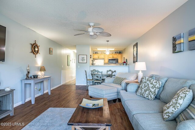 living room with dark hardwood / wood-style flooring, ceiling fan, and a textured ceiling