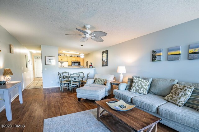 living room with hardwood / wood-style flooring, ceiling fan, and a textured ceiling