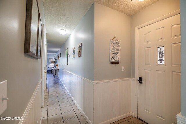 hall featuring light tile patterned floors and a textured ceiling