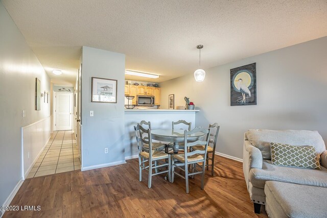 dining area with light hardwood / wood-style floors and a textured ceiling