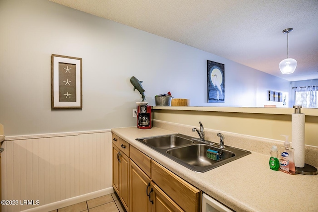 kitchen with sink, light tile patterned floors, hanging light fixtures, and a textured ceiling