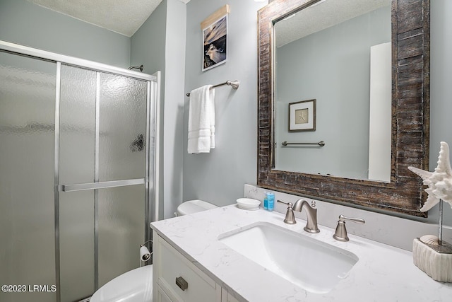 bathroom with vanity, toilet, an enclosed shower, and a textured ceiling