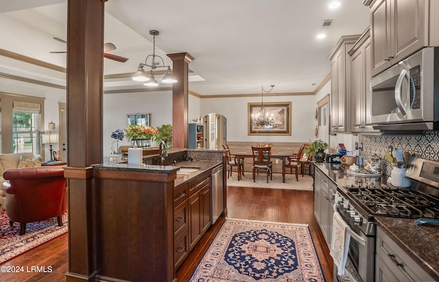 kitchen featuring dark wood-type flooring, appliances with stainless steel finishes, and hanging light fixtures