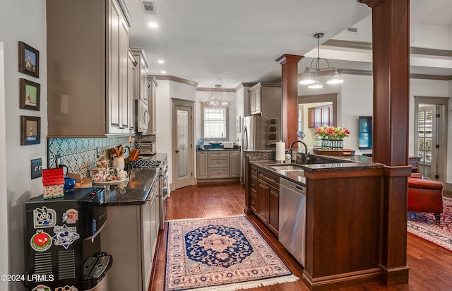 kitchen with ornate columns, decorative light fixtures, dark hardwood / wood-style floors, stainless steel appliances, and backsplash