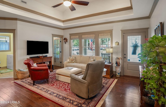 living room with crown molding, ceiling fan, dark hardwood / wood-style floors, washer / dryer, and a raised ceiling