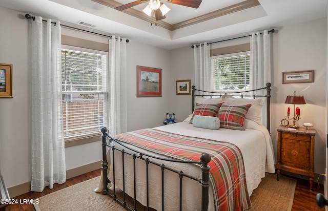 bedroom with multiple windows, ornamental molding, a raised ceiling, and ceiling fan