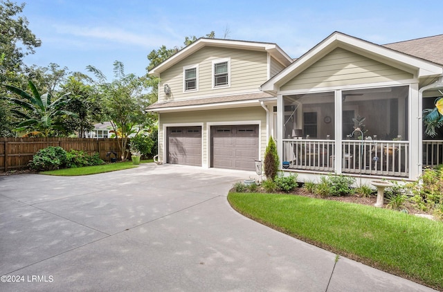 view of front facade featuring a garage, a front lawn, and a sunroom