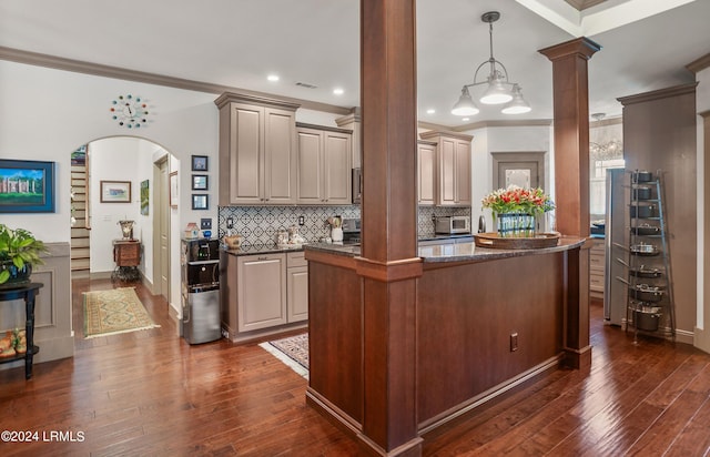 kitchen with dark wood-type flooring, ornate columns, crown molding, tasteful backsplash, and decorative light fixtures