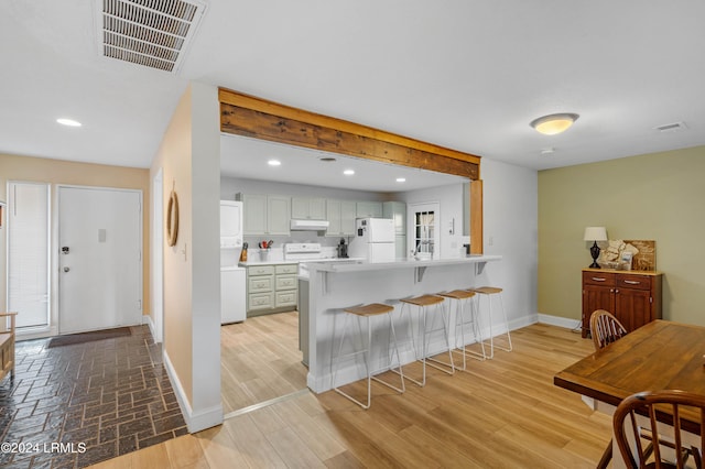 kitchen featuring a breakfast bar, white cabinets, white refrigerator, kitchen peninsula, and light hardwood / wood-style flooring