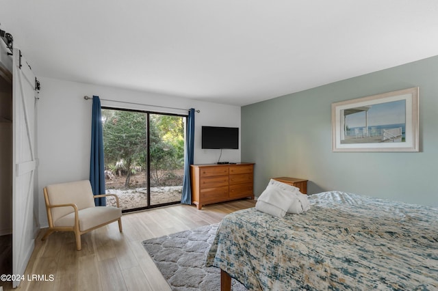 bedroom featuring a barn door, access to exterior, and light hardwood / wood-style flooring