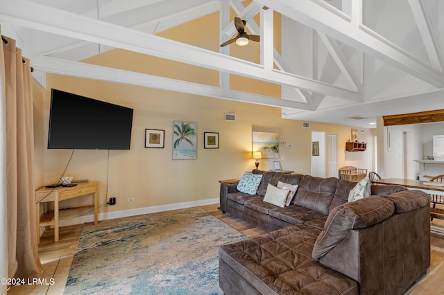 living room with ceiling fan, light wood-type flooring, and a high ceiling