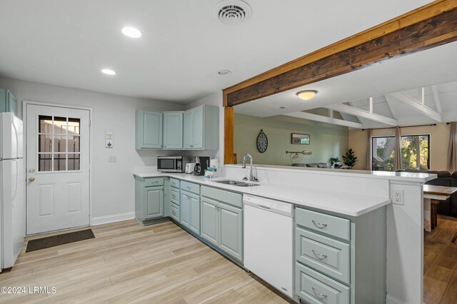 kitchen with sink, white appliances, light hardwood / wood-style flooring, vaulted ceiling with beams, and kitchen peninsula