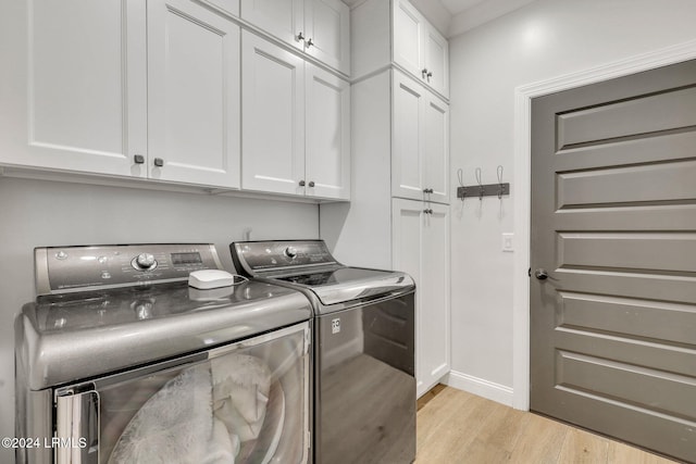 washroom with crown molding, light hardwood / wood-style floors, cabinets, and washing machine and clothes dryer