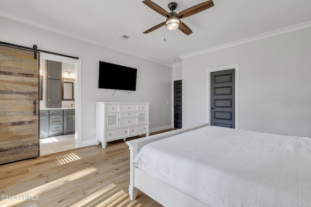 bedroom with ensuite bath, light hardwood / wood-style flooring, ornamental molding, ceiling fan, and a barn door