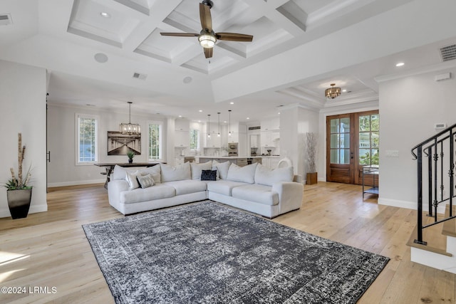 living room featuring beamed ceiling, ornamental molding, coffered ceiling, and light wood-type flooring