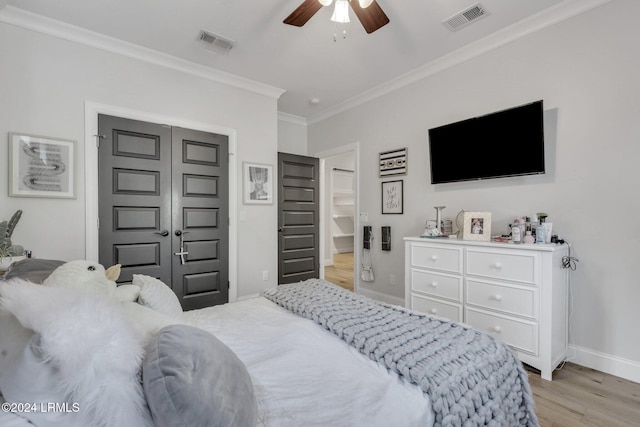 bedroom with ornamental molding, light hardwood / wood-style flooring, ceiling fan, and a closet