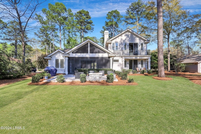 rear view of house featuring a balcony, a yard, and a patio