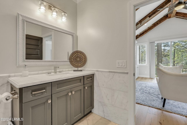 bathroom featuring vanity, wood-type flooring, lofted ceiling with beams, and tile walls