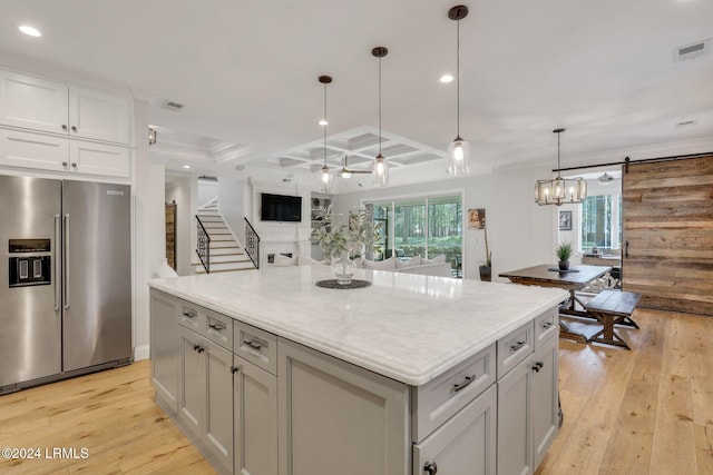 kitchen featuring coffered ceiling, decorative light fixtures, a center island, high quality fridge, and a wealth of natural light