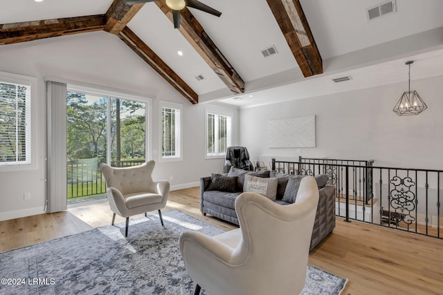 living room with lofted ceiling with beams, ceiling fan with notable chandelier, and light wood-type flooring