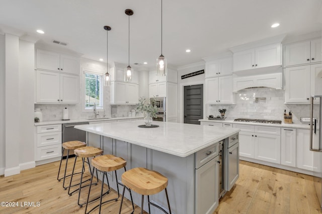 kitchen featuring a breakfast bar, sink, a kitchen island, stainless steel appliances, and white cabinets