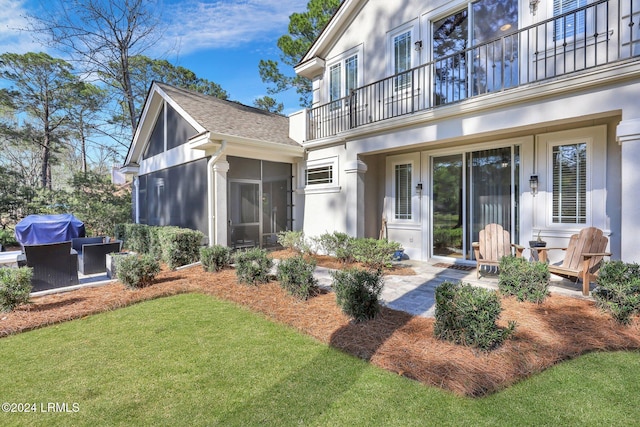 back of house with a lawn, a sunroom, and a balcony