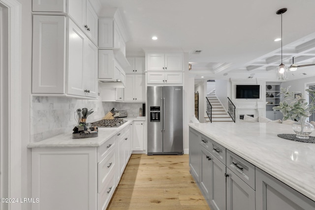 kitchen with high end fridge, white cabinetry, light stone counters, hanging light fixtures, and light hardwood / wood-style floors