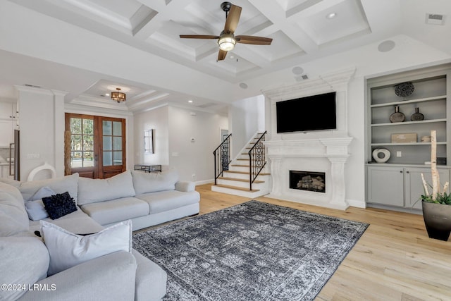 living room featuring a large fireplace, coffered ceiling, and light wood-type flooring