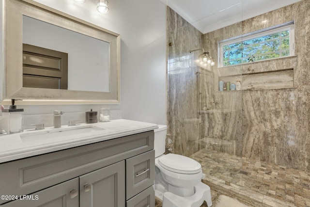 bathroom featuring a tile shower, vanity, and toilet